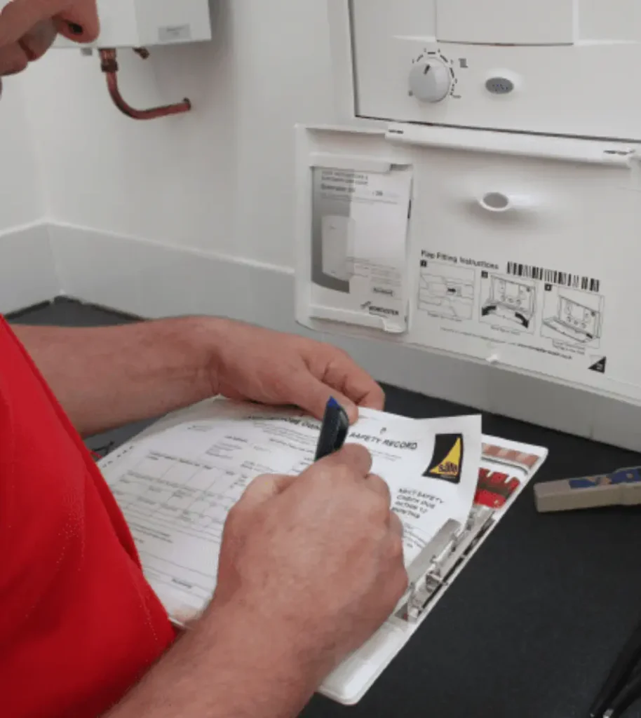 A person in a red shirt, possibly a landlord, filling out a form on a clipboard in front of a gas appliance.