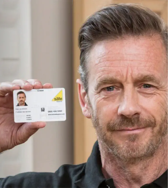 A man with short hair and a beard holds up an gas safe registered ID card close to his face, looking every bit the part of a meticulous agent.