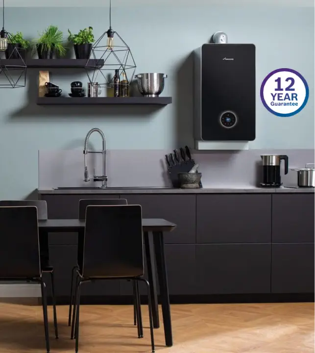 Modern kitchen with dark cabinets, a wall-mounted boiler boasting a "12 Year Guarantee," hanging shelves filled with kitchen items, and a table with chairs.
